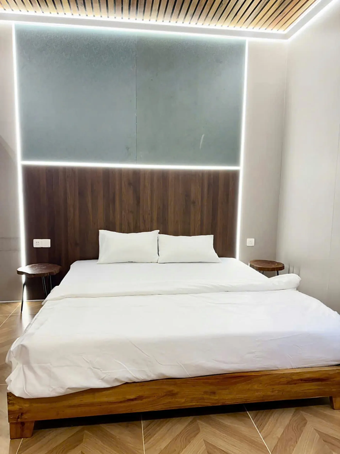 Căn giường đôi: giường King, đầu giường gỗ, trần tre có đèn hắt